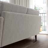Neutrales GRILLSTORP-Sofa mit schlanken Linien, weichen Kissen und dunklen Holzbeinen in der Nähe eines Fensters.