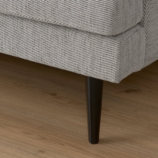 Nahaufnahme eines schlanken, modernen Sofas mit spitz zulaufenden Beinen. Grau gemusterter Stoff, hochwertiges Design.
