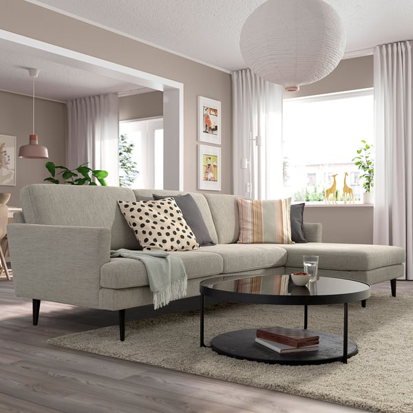 Modernes Wohnzimmer mit grauem Sofa GRILLSTORP; Große Kissen, hohe Beine. In der Mitte auf Teppich, mit rundem Couchtisch, dekorativ beleuchtet.