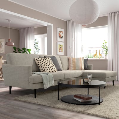 Modernes Wohnzimmer mit grauem Sofa GRILLSTORP; Große Kissen, hohe Beine. In der Mitte auf Teppich, mit rundem Couchtisch, dekorativ beleuchtet.