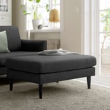 Modernes Wohnzimmer mit breitem GRILLSTORP grauem Stoffsofa und Ottomane. Leichtes Dekor mit Pflanzen und Lampe. Das Sofa hat dunkle Beine, bequeme Kissen.