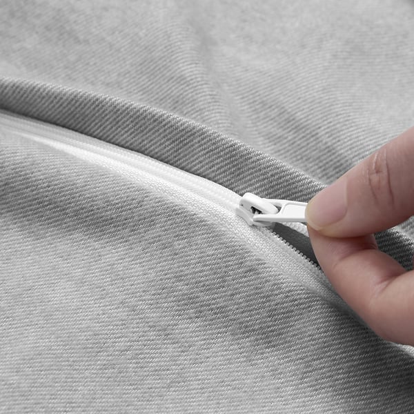 Der graue GROVSNÄRJA-Bettbezug mit einem Reißverschluss an der Hand zeigt seinen funktionalen weißen Reißverschluss.