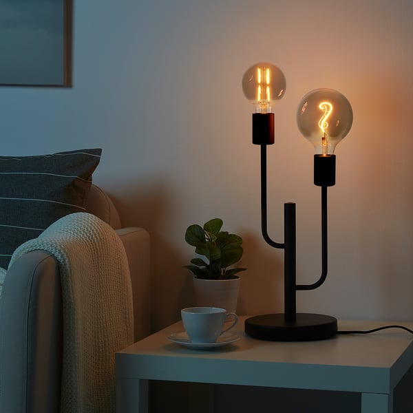 Schwarze HADDEBO-Lampe mit 2 Glühbirnen auf dem Beistelltisch.