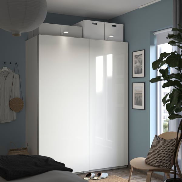 Ein modernes Schlafzimmer mit einem weißen, glänzenden Schiebeschrank, einer gestreiften Wand und einem gestreiften Stuhl.