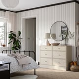 Schlafzimmer mit heller HAVSTA-Kommode neben Metallbett, sechs Schubladen, minimalistisches Design.
