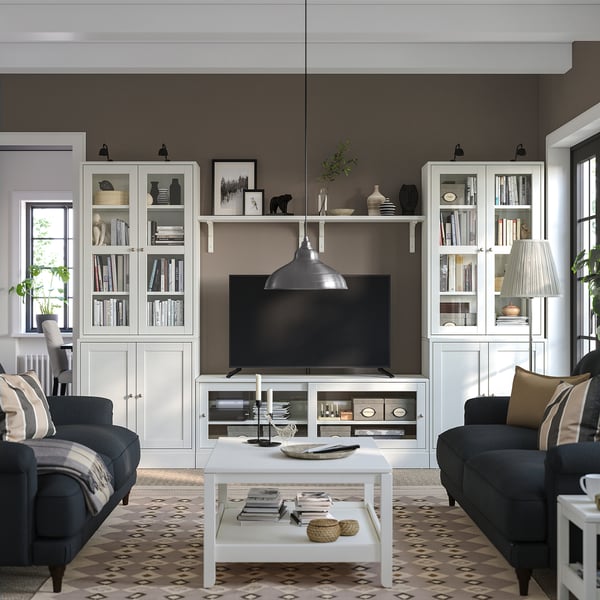 Modernes Wohnzimmer mit HAVSTA-Möbeln: Glastüren, TV-Bank, Sofas, Couchtisch an dunkler Wand.