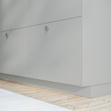 Moderne Küchenschränke mit schlankem, hellgrauem Finish und minimalistischen runden Griffen.