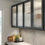 Moderne Küche mit schwarzem HEJSTA-Schrank, Schilfglastüren und Topfkräutern.