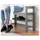 Person, die einen schwarzen Schuh anzieht, steht in der Nähe eines grauen HEMNES-Schuhregals mit mehreren Regalen.