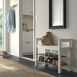 Weißes HEMNES Schuhregal mit einer beigen Tasche, in der Nähe eines Kleiderhakens und der Küche.