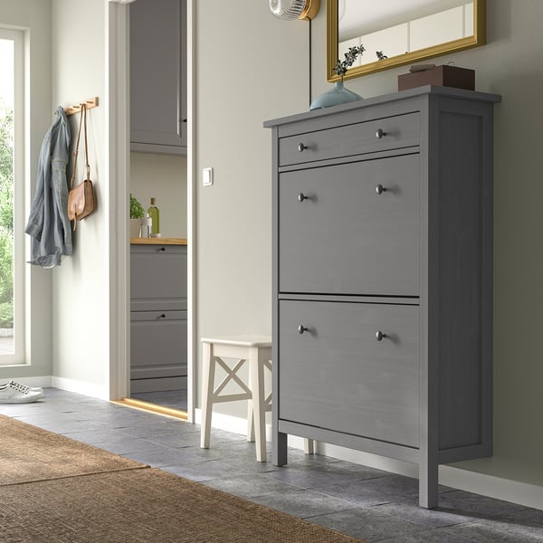 Grauer HEMNES Schuhschrank mit 3 Fächern an der Wand, höher als ein weißer Hocker, passt unter den Eingangsspiegel.