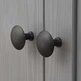 Dunkle Metallknöpfe, die an einer grauen Holzoberfläche, wahrscheinlich einer Schranktür, befestigt sind, zeigen ein schlankes und modernes Design.