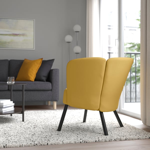 Ein modernes Wohnzimmer mit einem kräftigen gelben Stuhl, einem grauen Sofa und hellen Akzenten.