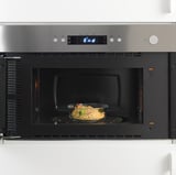 Mikrowelle mit Mahlzeit im Inneren, digitale Steuerung, einfache Aufbewahrung, wärmt Speisen auf.