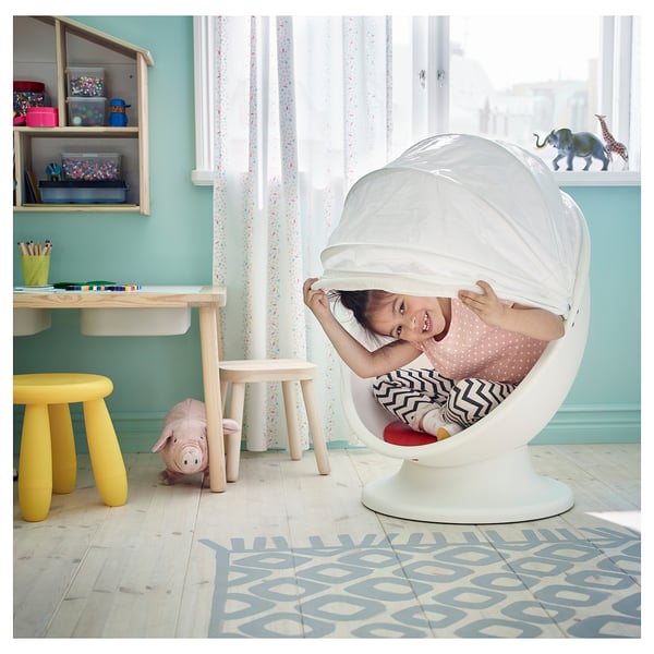 Mädchen in weißem IKEA-Stuhl, Zimmer mit gelbem Hocker, Tisch und Spielzeug.