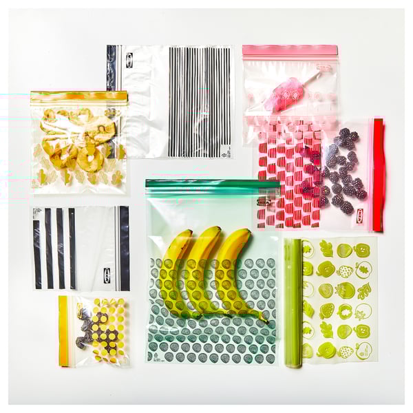 Tüten mit Obst und Snacks auf weißer Oberfläche