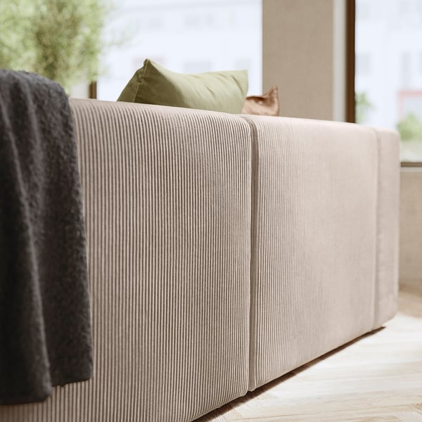Modernes beiges Sofa mit grünem Kissen, gemütlich und stilvoll.