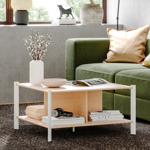 Modernes Wohnzimmer mit JÄTTESTA Couchtisch aus Bambus, weiße Beine. Grünes Sofa, dekorative Vase, Bücher und Kopfhörer. Sauberes, schlankes Design.
