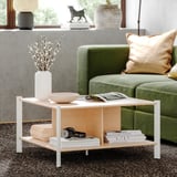 Modernes Wohnzimmer mit JÄTTESTA Couchtisch aus Bambus, weiße Beine. Grünes Sofa, dekorative Vase, Bücher und Kopfhörer. Sauberes, schlankes Design.