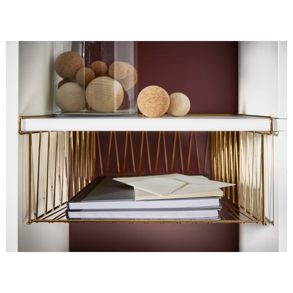 Goldener KALLAX Regal-Organizer mit Papierstapeln und kugelförmigem Dekor in Glasvase.