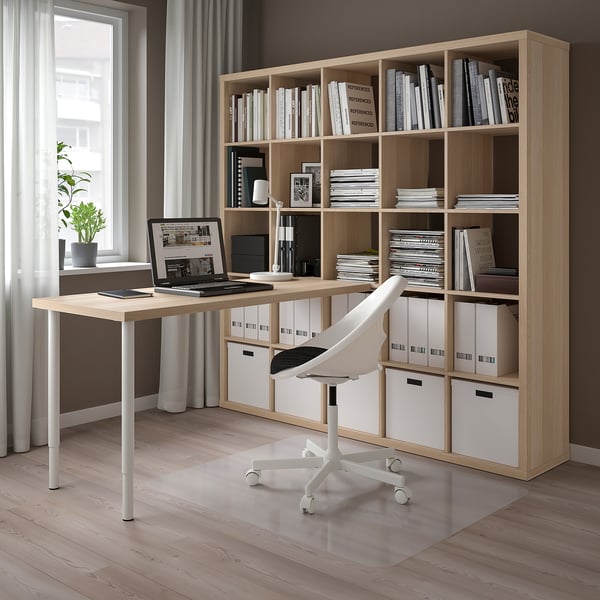 Modernes Homeoffice mit hellem KALLAX Bücherregal und Schreibtisch aus Holz. Weißer Drehstuhl, Laptop und Aufbewahrungsboxen.