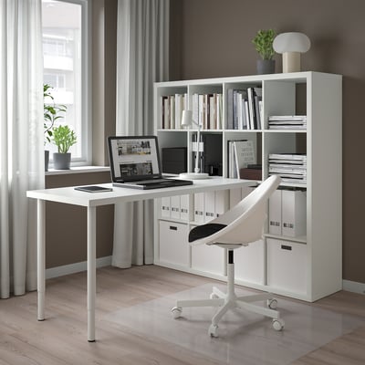 Modernes, minimalistisches Home Office mit weißem KALLAX Regal, Schreibtisch und Stuhl. Großes Fenster mit durchsichtigen Vorhängen, Holzboden.