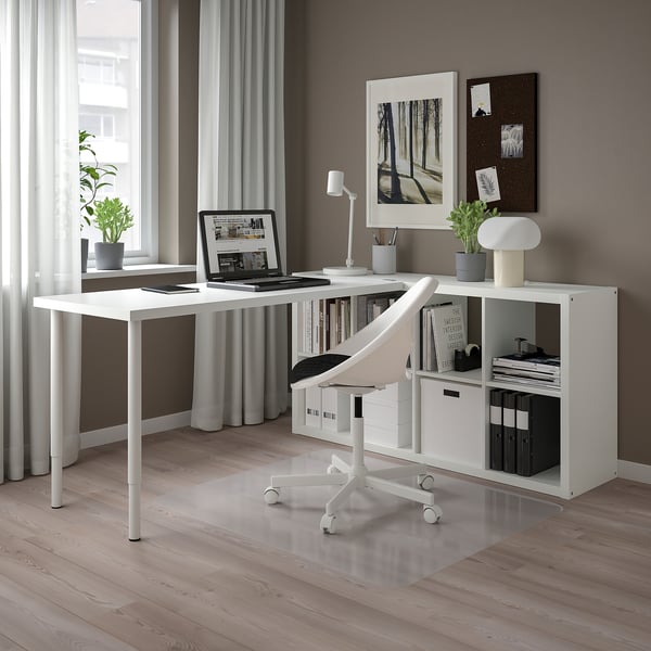 KALLAX Schreibtisch mit Laptop, Pflanzen, Büchern und Büromaterial. Eckfenster, durchsichtige Vorhänge.