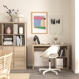 Homeoffice mit KALLAX Schreibtisch, Drehstuhl, Laptop, Lampe, Kunstwerk und Bücherregal.