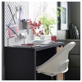 Modernes Homeoffice mit dunklem Schreibtisch, weißem Stuhl, Steckbrett, Pflanzen und Büchern. Schreibtisch fasst Papiere und Tasse.