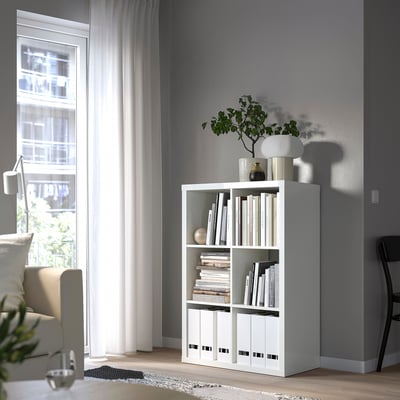 KALLAX Bücherregal mit Dekor am Fenster, Stühlen, modern.