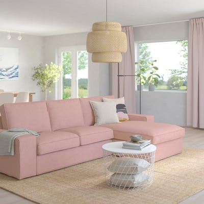 Rosa KIVIK Sofa mit Chaiselongue, Kissen, Lampe und großen Fenstern.