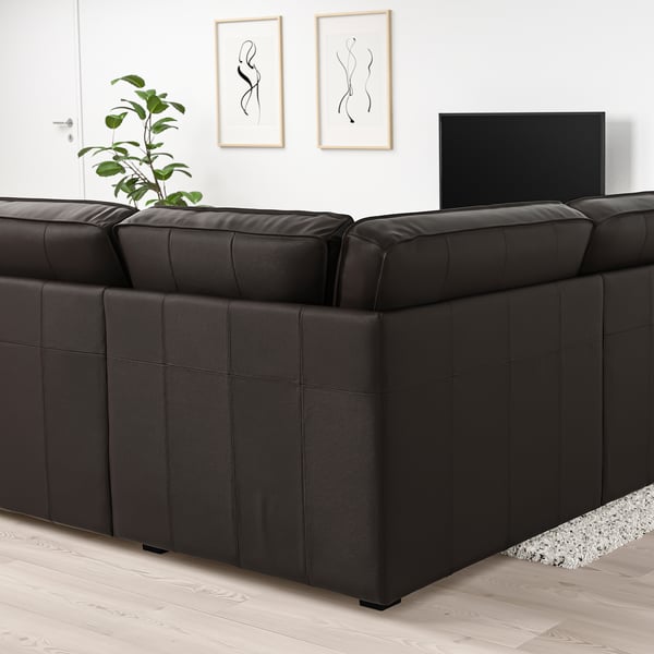 Modernes schwarzes KIVIK-Sofa, große und tiefe Sitze, weiches Leder, schlichtes Design, Ecken mit Kunstdrucken und Pflanzen.