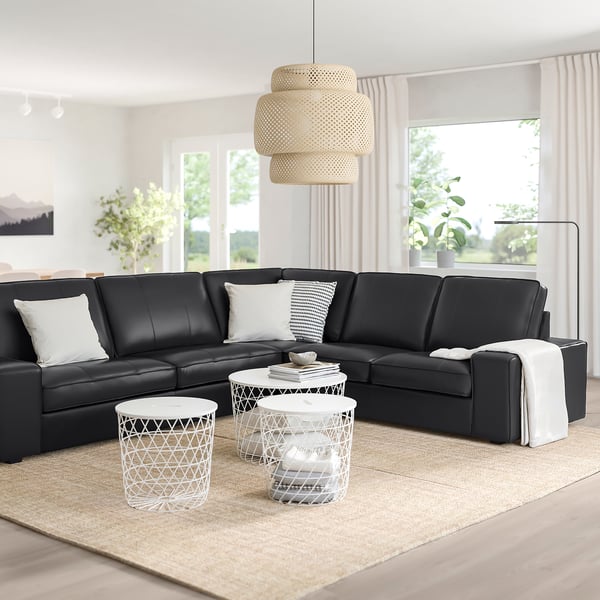 Modernes Wohnzimmer mit KIVIK-Sektion, Beistelltischen, großen Fenstern, Teppich, Pendelleuchte, minimalistischem Design.