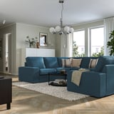 Modernes Wohnzimmer: großes blaues KIVIK-Sofa mit weichen Kissen, stilvoller Couchtisch, heller Holzboden und große Fenster.