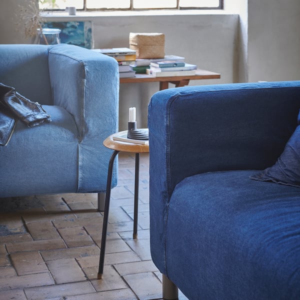 Gemütliche blaue Denim-Sofagarnitur mit modernem, minimalistischem Design. Bequeme Kissen, abnehmbare Bezüge, kleiner Beistelltisch mit Kerze.
