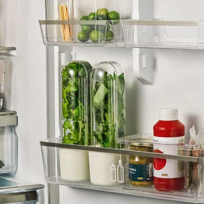 Kühlschrank mit durchsichtigen Behältern für Kräuter, Limetten und Gewürze, um die Produkte frisch zu halten.