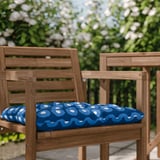 Zwei Holzstühle mit blau gemusterten Kissen im Freien.