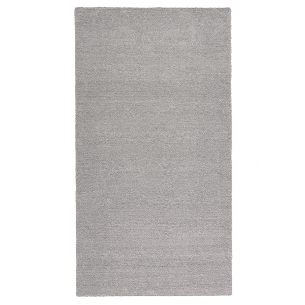 Ein hellgrauer, rechteckiger Teppich mit Glanz aus recyceltem Polyester mit einem weichen, dicken Flor.