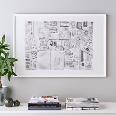 Gerahmte Collage-Kunst mit Passstempeln an der Wand; stand auf einem Regal mit Büchern und Pflanzen.