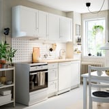 Moderne weiße KNOXHULT-Küche mit Schränken, Theke, Backofen, Geschirrspüler, minimalistischem Design.