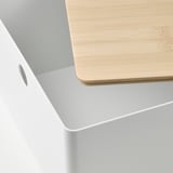 Nahaufnahme eines Bambusdeckels auf einer weißen Schachtel, der seine glatte Oberfläche und natürliche Maserung zur Geltung bringt und Qualität und Handwerkskunst betont.