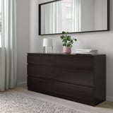 Dunkelbraune Kommode mit Spiegel und Schubladen. Lampe, Bücher, Pflanze obendrauf. Teppich, sicher, verankert.