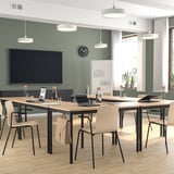 Moderner Konferenzraum mit Stühlen aus hellem Birkenfurnier, rechteckigen Tischen, großem Bildschirm und Hängelampen. Die Stühle sind sauber, leicht und stapelbar.