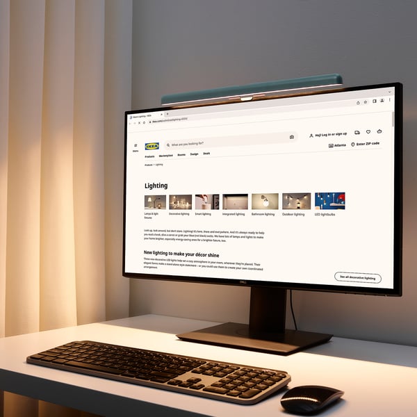 Schreibtisch mit Monitor, Tastatur, Maus und LAGERGÅNG Lampe.