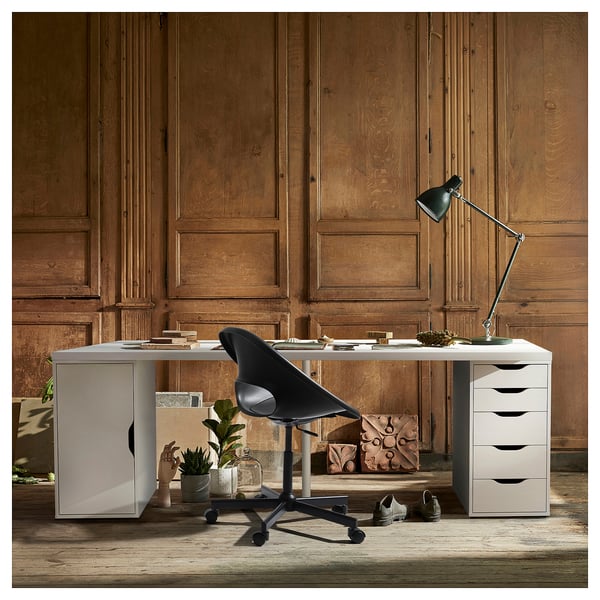 Home-Office-Einrichtung mit weißem LAGKAPTEN-Schreibtisch, schwarzem Stuhl, Lampe und Aufbewahrungseinheiten. Holzgetäfelte Wände werten den Arbeitsbereich auf.