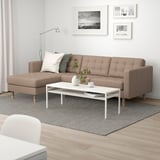 Modernes Wohnzimmer: beiges Lanskrona-Sofa, weißer Couchtisch, grauer Teppich, Wandkunst.