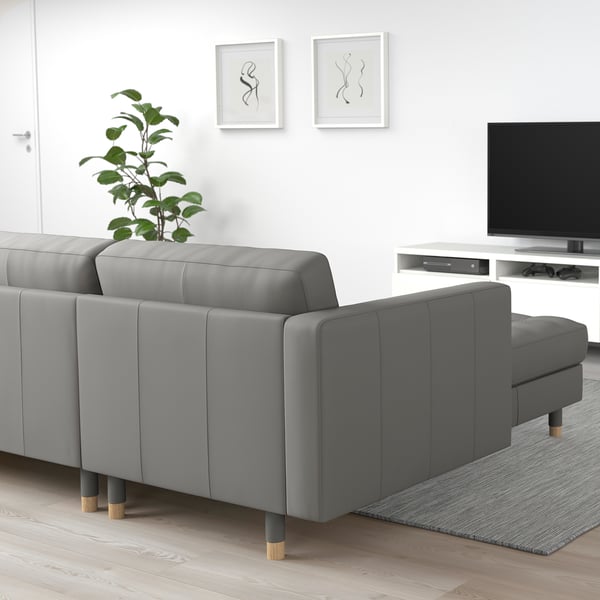 Modernes Wohnzimmer mit grauem LANDSKRONA-Sofa, elegantem TV-Ständer und Wandkunst. Das Sofa ist groß, mit Kissen und Holzbeinen.