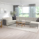 Modernes Wohnzimmer mit großem grauem L-förmigem LANDSKRONA-Sofa, Couchtisch aus Holz und großen Fenstern.
