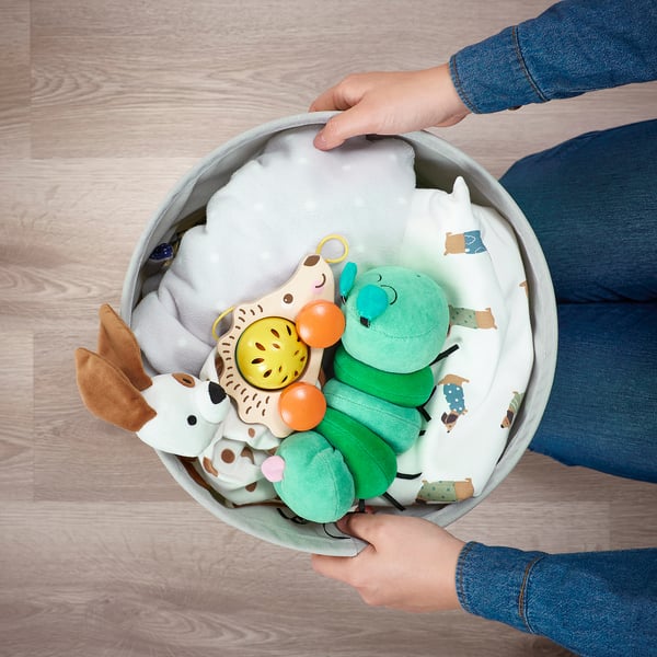 Kinderhand greift in eine Tasche mit buntem Spielzeug. Weiche, leichte, wendbare Aufbewahrungstasche für das Kinderzimmer.