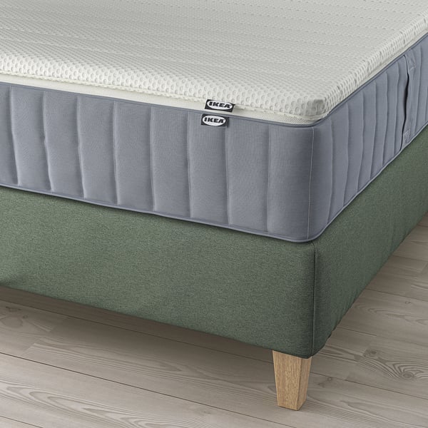 Ein LILLFJÄLLET Boxspringbett mit schrägem Kopfteil und abnehmbarem, waschbarem Matratzenbezug.